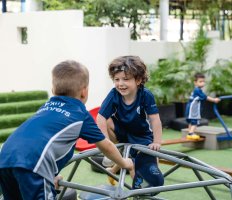 Two Primary students climbing on a campus playground