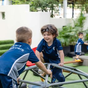Two Primary students climbing on a campus playground